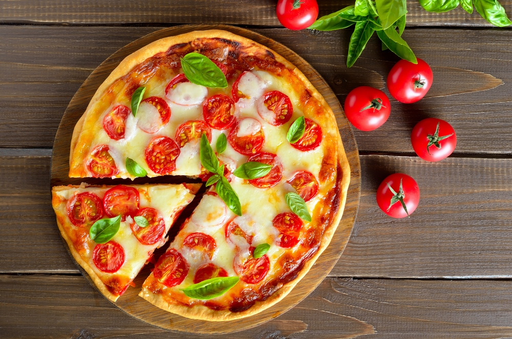 Tábua com pizza marguerita e tomates ao lado