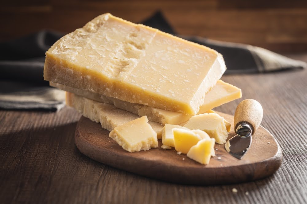 Queijo parmesão Grana Padano cortado em fatias em cima de tábua