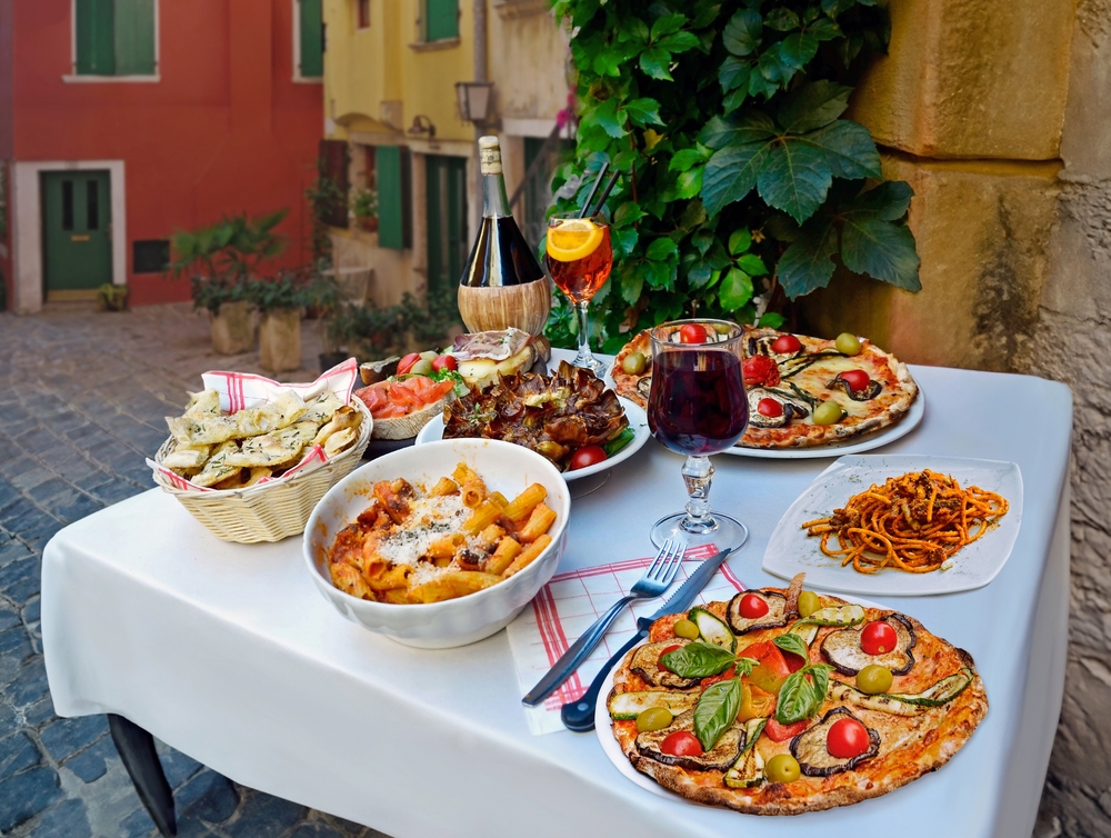 Mesa de jantar com pizzas, massas e uma garrafa de vinho