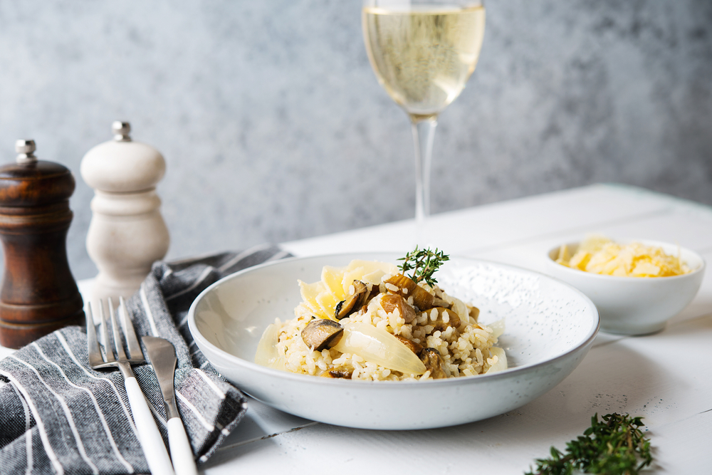 Prato com risoto funhi ao lado de pote com queijo parmesão