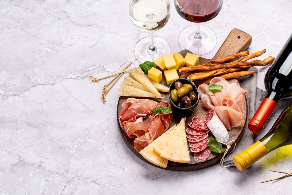 Tábua de frios com queijos, grissini, salame, presunto e azeitonas