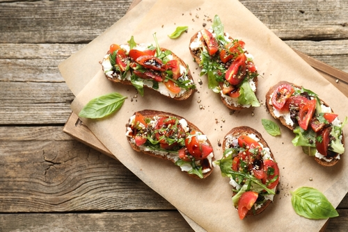 Na imagem, há cinco bruschettas italianas em cima de mesa