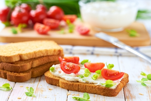 Na imagem, há um toast com. creme de ricota e tomates cortados